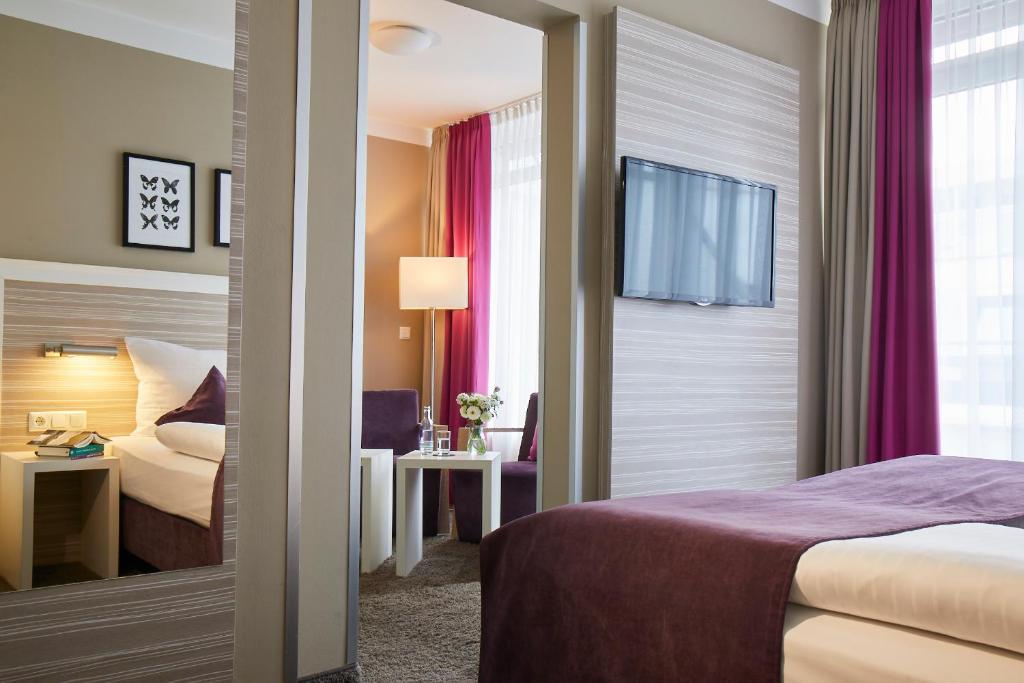 a hotel room with a bed and a desk and a bed at Hotel Mirabell by Maier Privathotels in Munich