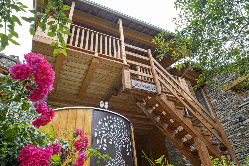 een houten trap aan de zijkant van een gebouw met roze bloemen bij Amelu' in Ostana
