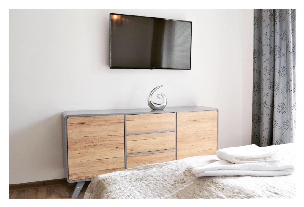 a bedroom with a dresser with a television on the wall at SGL apartments Lavickova in Trenčín