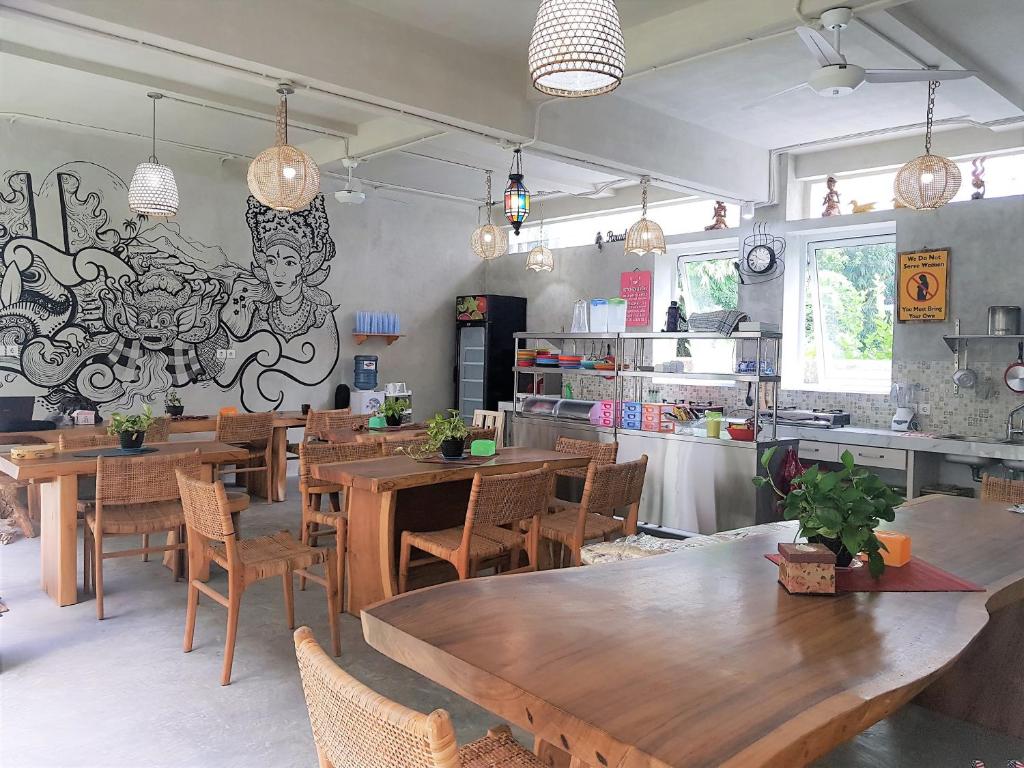 ジンバランにあるBali Bobo Hostelの木製のテーブルと椅子、壁画のあるレストラン