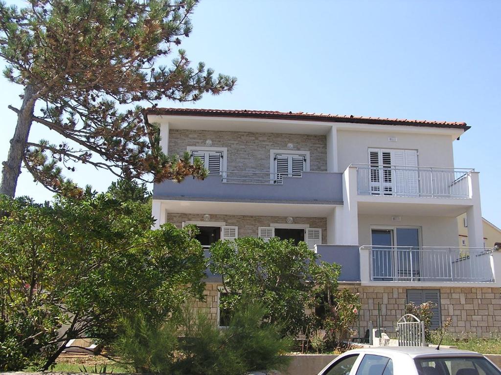 ein weißes Haus mit einem davor geparkten Auto in der Unterkunft Apartman Marin in Šilo