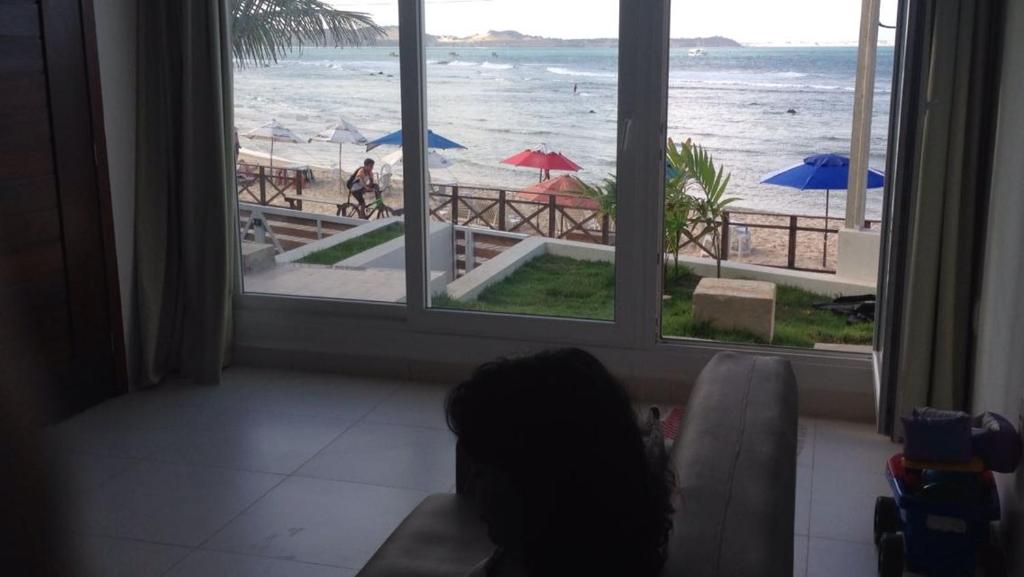 a living room with a view of the beach from a window at Imóvel na Beira-Mar in Pipa
