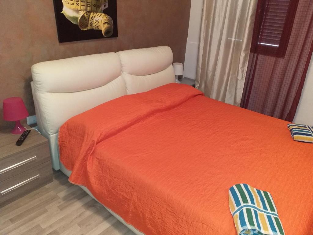 a bedroom with a white bed with an orange blanket at BED&FLY NEAR AIRPORT FONTANAROSSA reception h24 in Catania