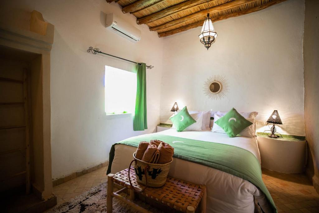 a bedroom with a bed with green sheets and a window at Riad Kasbah Aiour in Merzouga