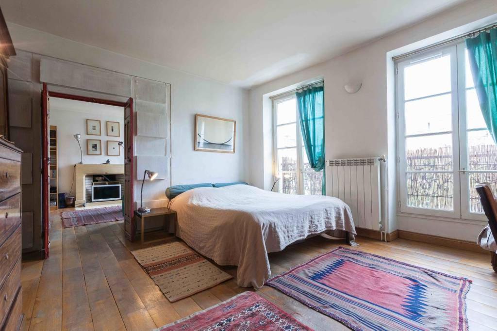 ein Schlafzimmer mit einem Bett und einem großen Fenster in der Unterkunft séjour Haut Marais in Paris