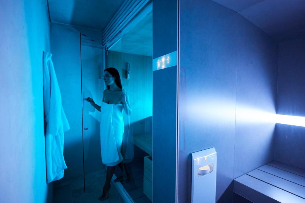 a woman standing in a bathroom with a glass door at Musae Relais & SPA in Polignano a Mare