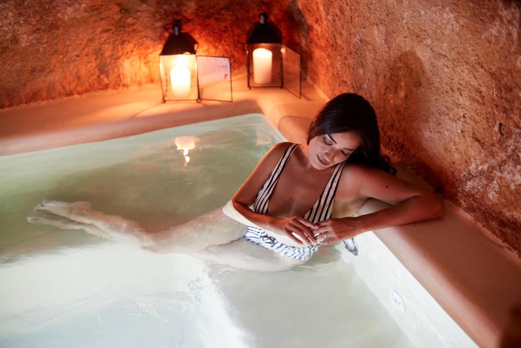 a woman is sitting in a hot tub at Musae Relais & SPA in Polignano a Mare