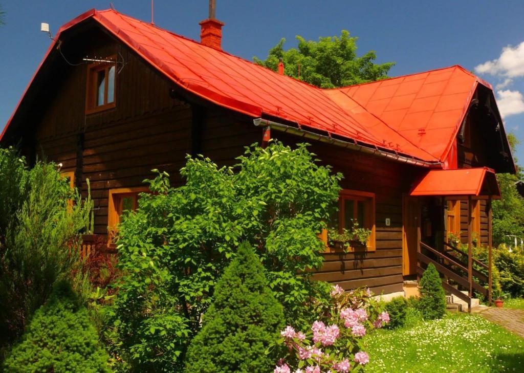 a wooden house with a red roof and some bushes at Chaty Javorina in Javorina