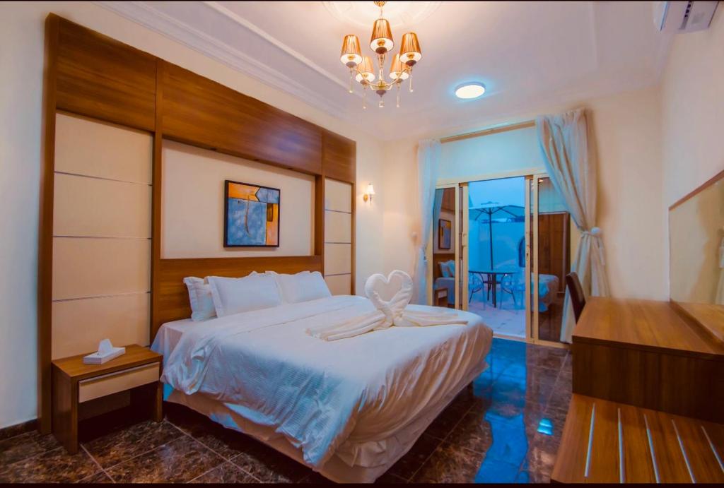 Un dormitorio con una gran cama blanca y una lámpara de araña. en Arees Beach, en Rayyis