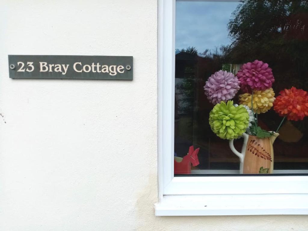 Una ventana con un jarrón con flores. en Bray Cottage, en Sidmouth