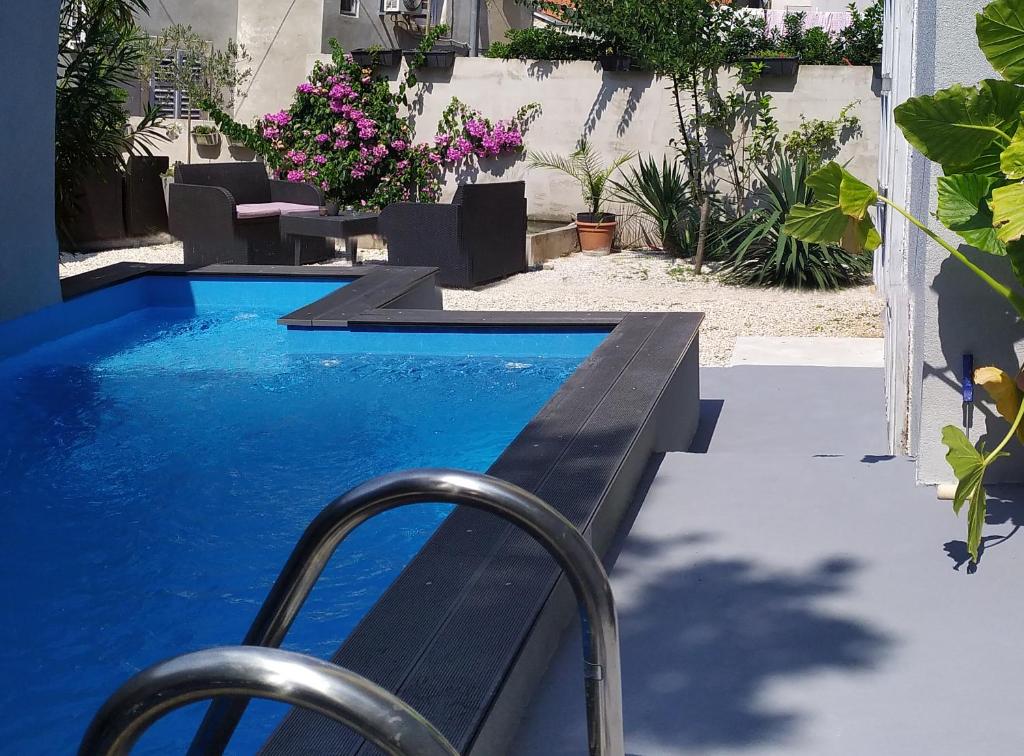 a swimming pool with a bench and a table and flowers at Captain Emo City Apartments in Pula
