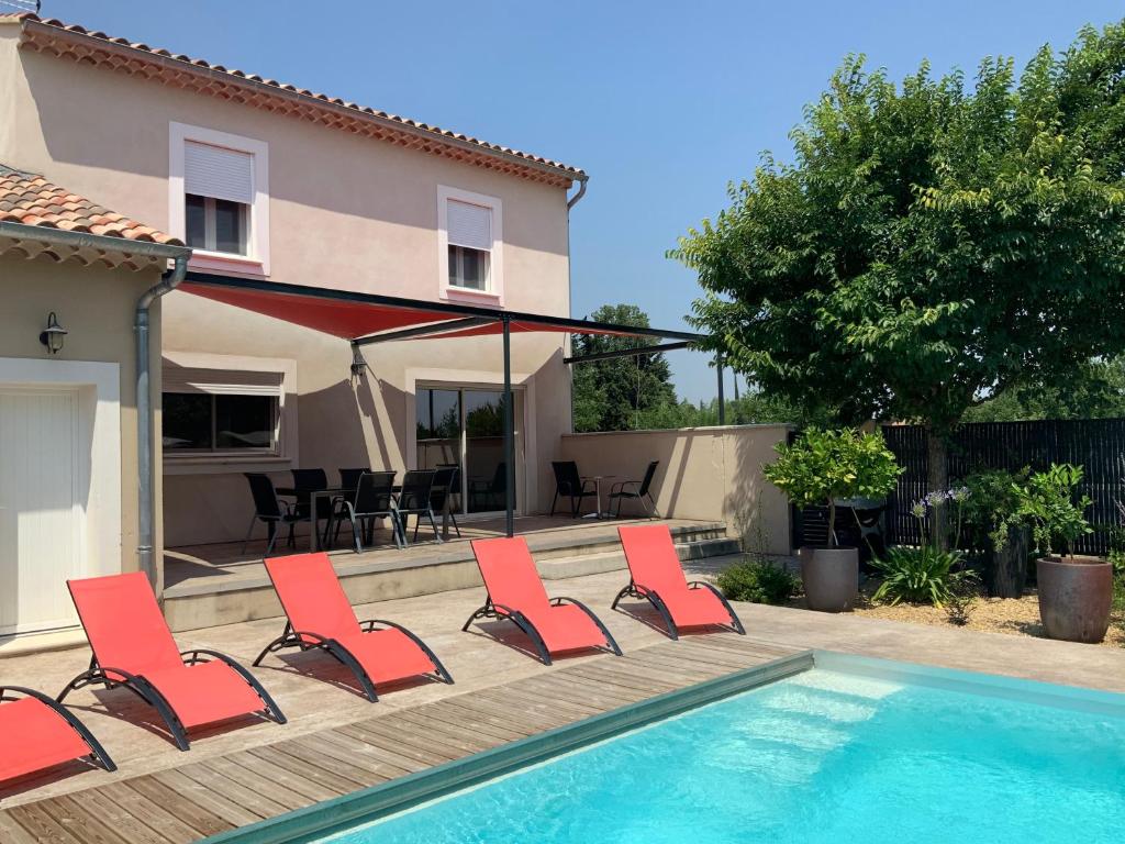 un grupo de sillas rojas sentadas junto a una piscina en La Maison de Caillette, en Camaret-sur-Aigues