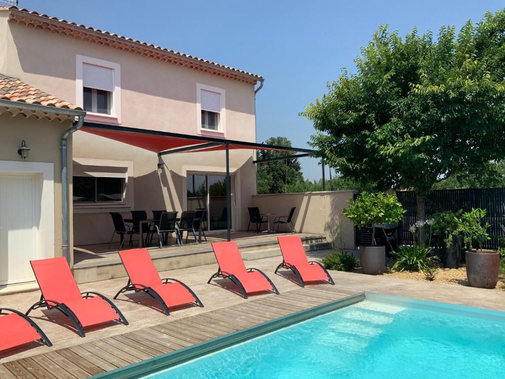 a group of red chairs sitting next to a swimming pool at La Maison de Caillette in Camaret-sur-Aigues