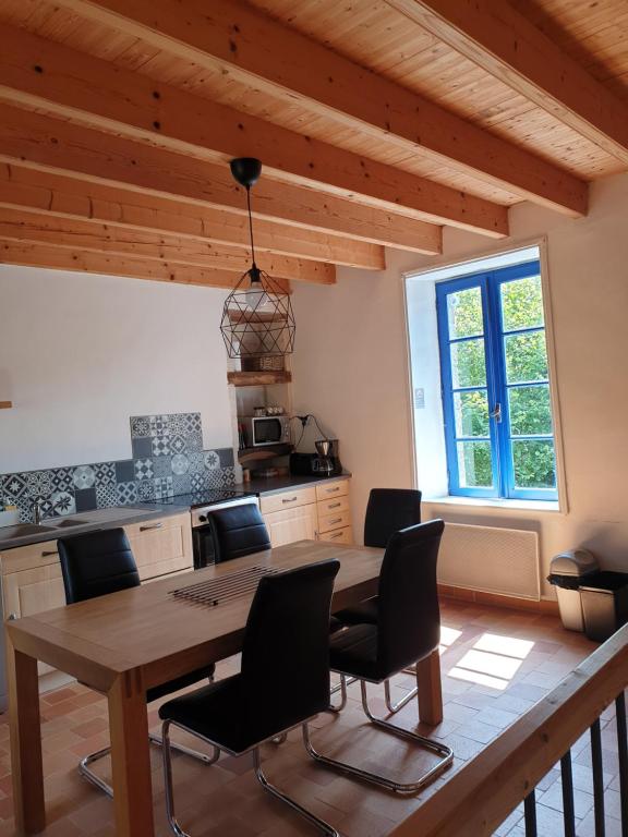 Treize-VentsにあるGîte les Pieds dans l'eau bord de Sèvre, 10 min du Puy du Foのキッチン(木製のテーブル、椅子付)、窓が備わります。