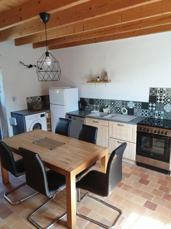 a kitchen with a wooden table and black chairs at Gîte les Pieds dans l&#39;eau bord de Sèvre, 10 min du Puy du Fo in Treize-Vents