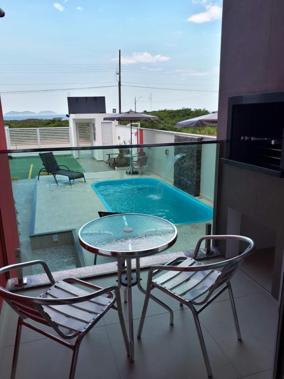 balcón con mesa y sillas y piscina en Beira Mar Village, en Pinheira