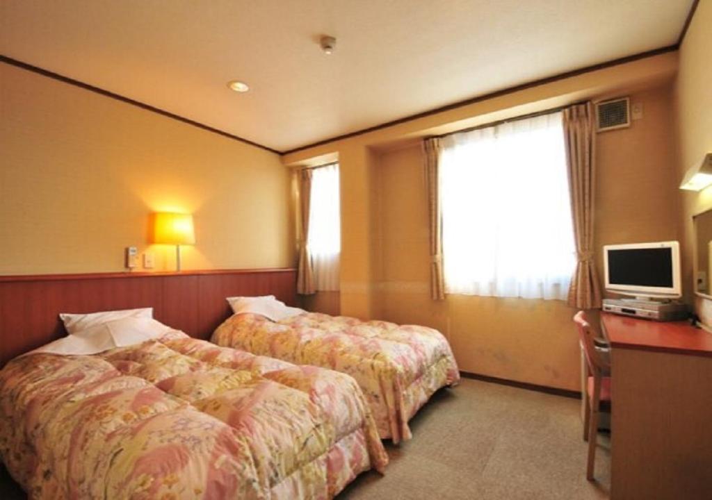 Omura - Hotel / Vacation STAY 46226 في Omura: غرفة فندقية بسريرين ومكتب وتلفزيون