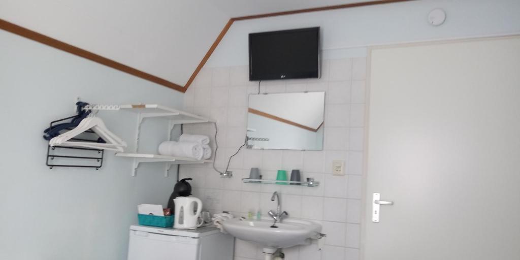 a bathroom with a sink and a tv on the wall at Noemie's Pension House in Volendam