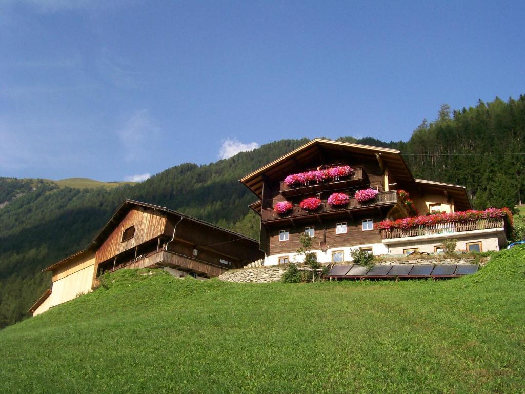 ein Gebäude mit Blumen auf einem Hügel in der Unterkunft Wachtlerhof in Matrei in Osttirol