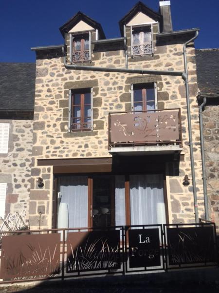 a tall stone building with two windows and a balcony at la petite forge in Saint-Saturnin