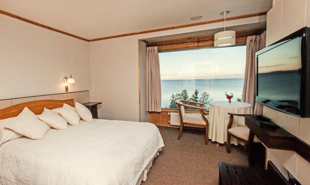 a hotel room with a bed and a large window at Hotel Elun, la mejor vista in Frutillar