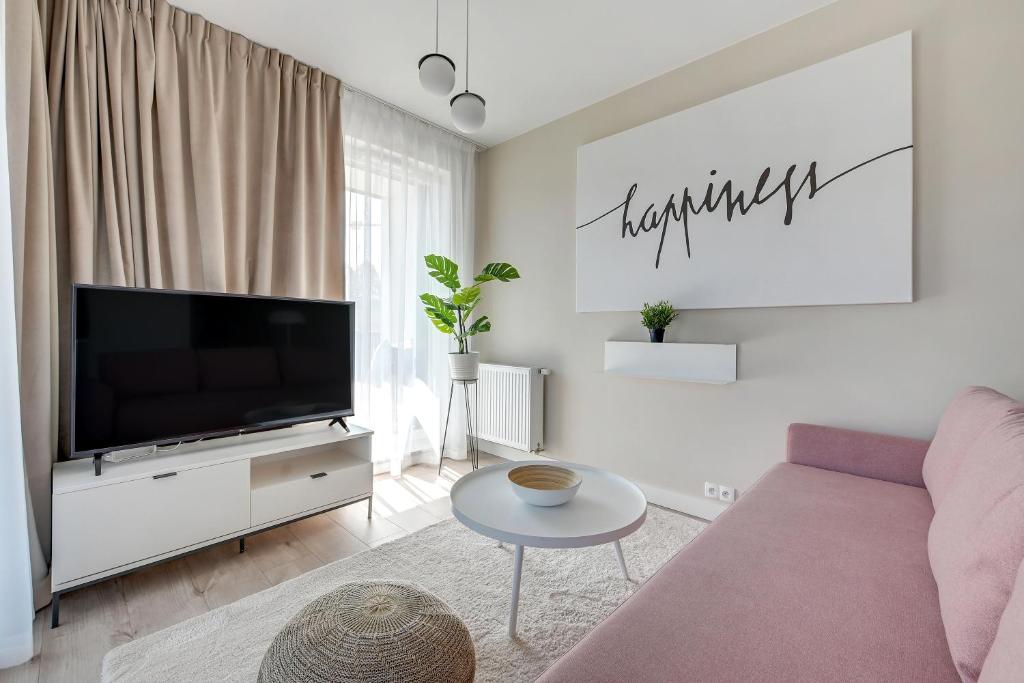 a living room with a couch and a tv at Wave Apartments - Olivia Park in Gdańsk