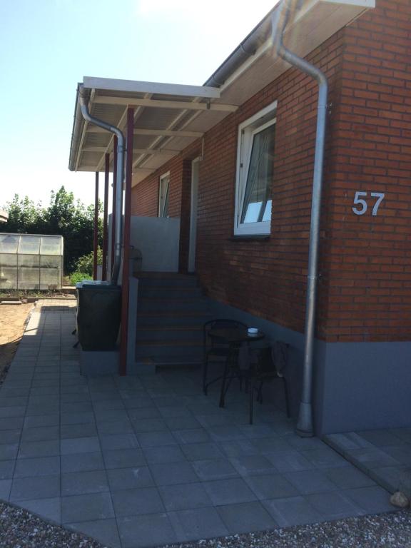 a patio with a table and chairs next to a brick building at Gæstehus Hovslund in Rødekro