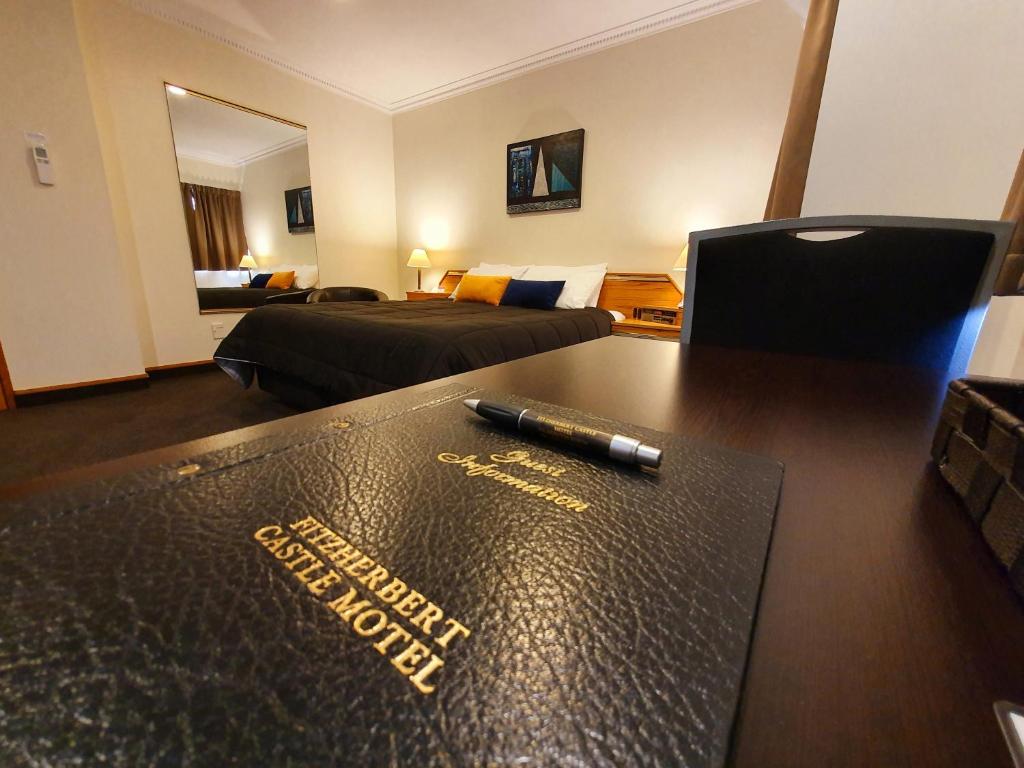a hotel room with a desk with a pen on it at Fitzherbert Castle Motel in Palmerston North