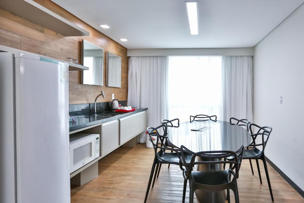 a kitchen with a table and chairs and a refrigerator at Roomo Praia de Boa Viagem Residencial in Recife