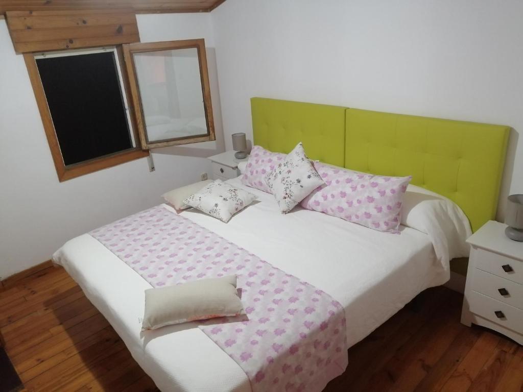 a bedroom with a bed with pink and white pillows at O Tipico in Ribadavia