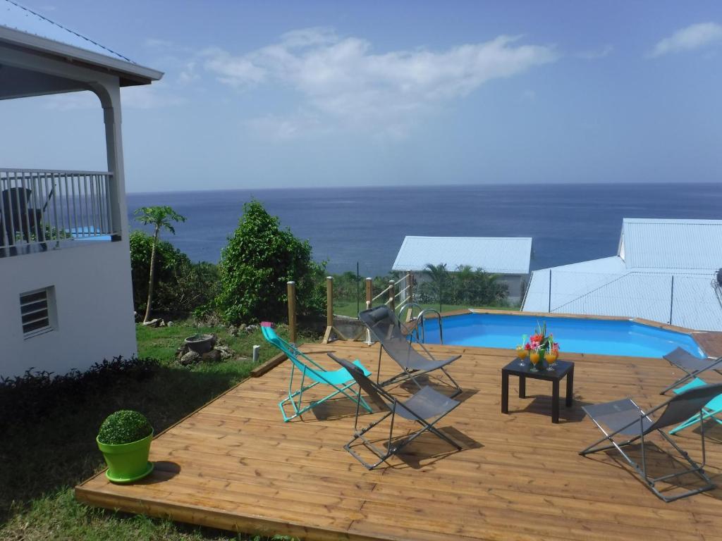 a deck with chairs and a table next to a pool at MAISON Vue et Accès Mer, piscine GUADELOUPE 6 personnes in Bouillante
