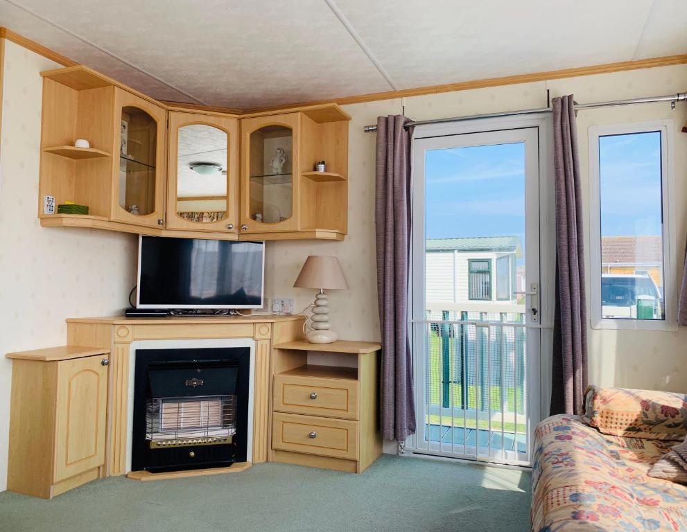a living room with a tv and a fireplace at Golden Sands Caravan Hire Ingoldmells- FREE in caravan wifi- Access included to the on site club house, sports bar, arcade, coffee shop We have beach access, a fishing lake and a laundrette in Ingoldmells