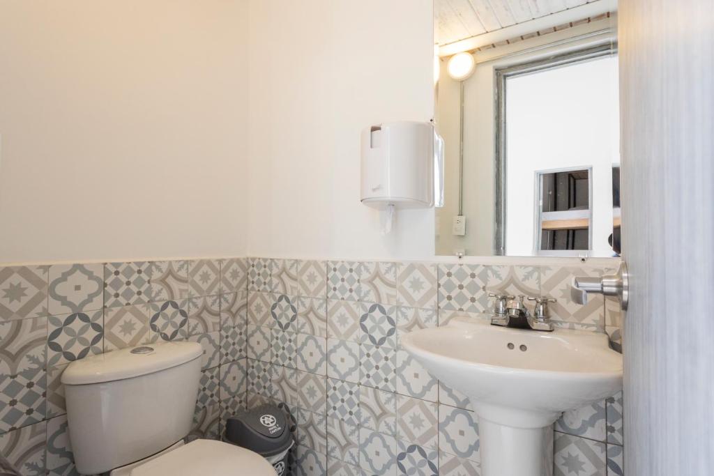 un bagno con lavandino, water e specchio di Gastón Coliving a Medellín