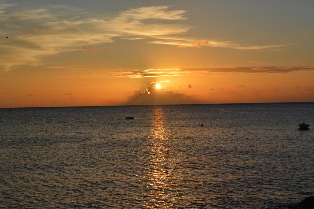 una puesta de sol sobre el océano con la puesta de sol en Middle Country 97-1 "la recette du bonheur" en Deshaies