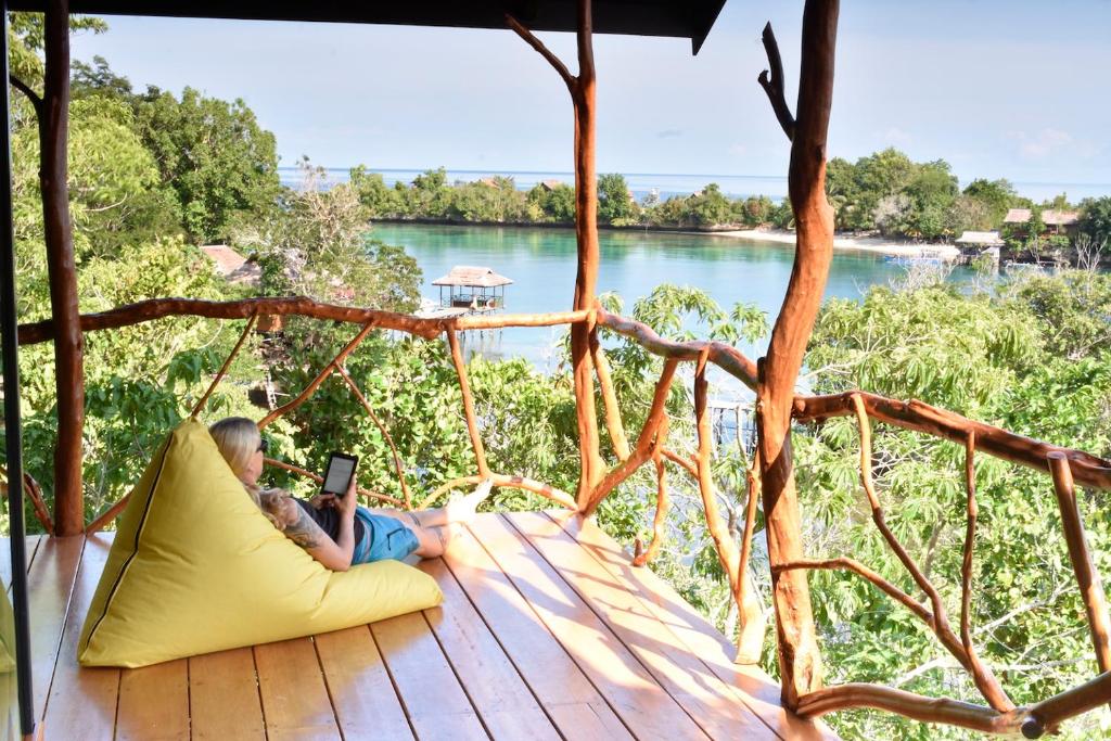 a boy laying on a pillow in a hammock with a tablet at Araya Dive Resort Togean in Bomba