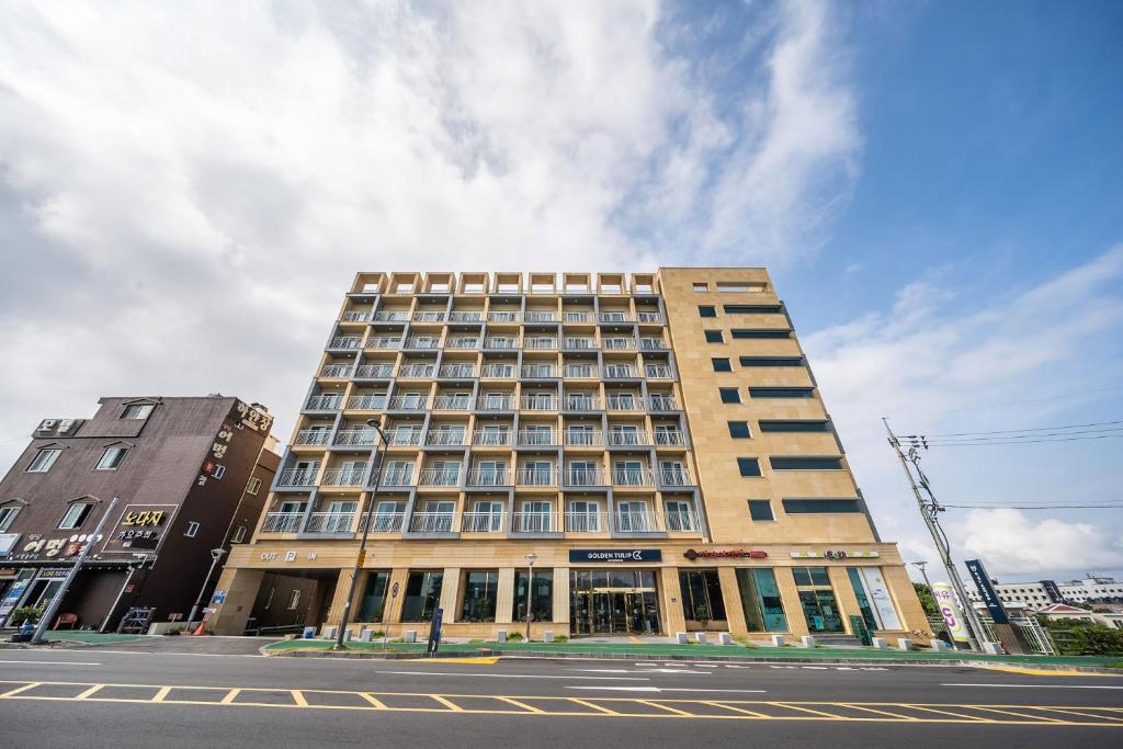 a large building on the corner of a street at Ktree Jeju Seongsan Hotel in Seogwipo