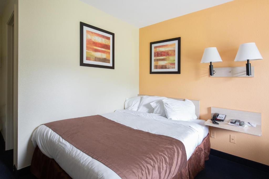 a hotel room with a bed and two pictures on the wall at Days Inn by Wyndham New Philadelphia in New Philadelphia