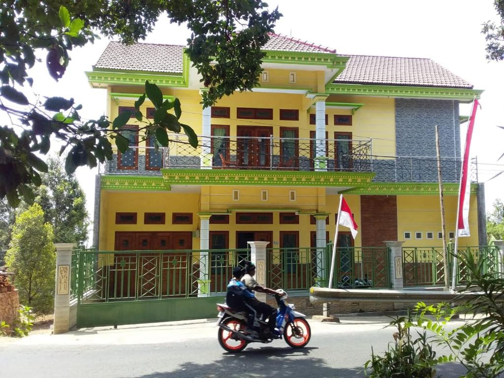a man riding a motorcycle in front of a yellow building at mas dylan homestay in Bromo