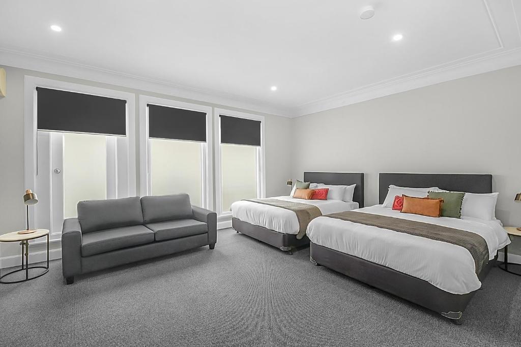 una habitación de hotel con 2 camas y una silla en Horse and Jockey Hotel Homebush en Sídney
