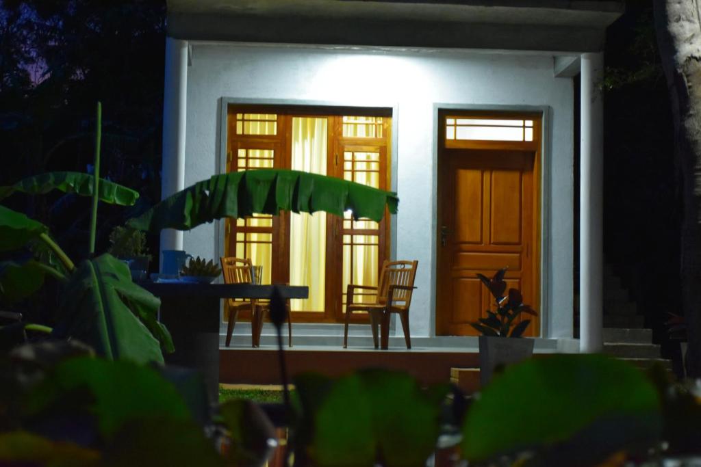 a house with two chairs and a table in front of it at Villa77 in Polonnaruwa