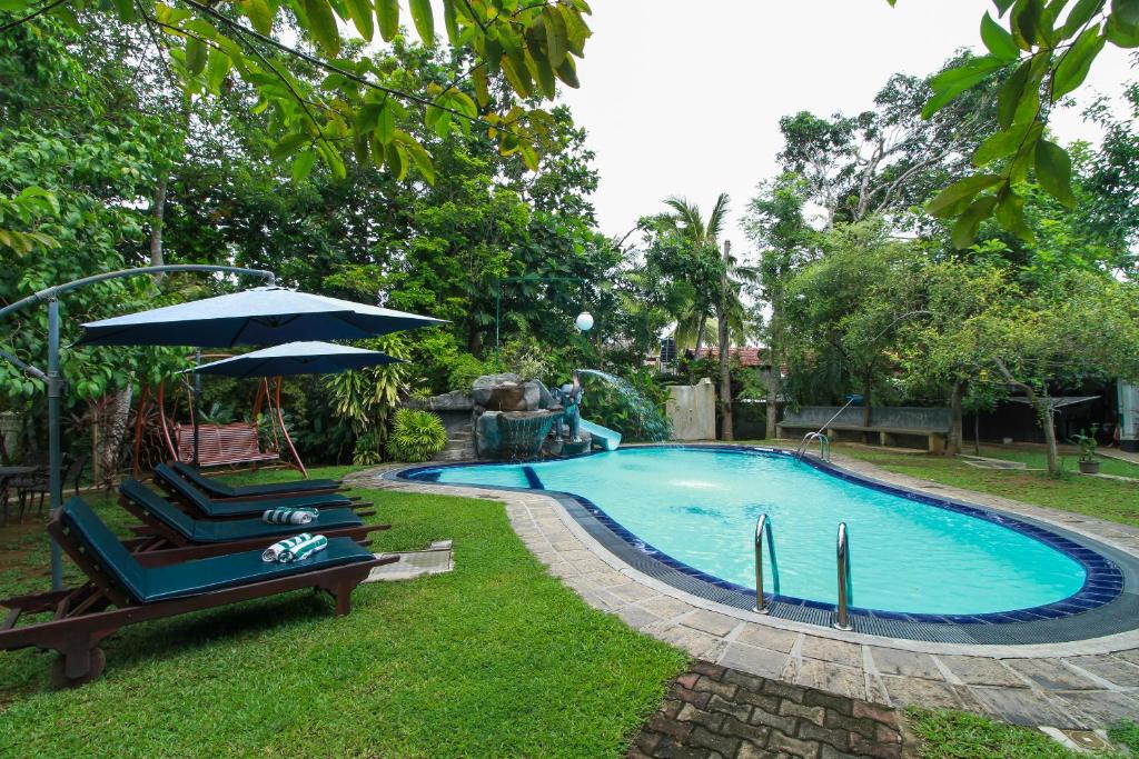 una piscina con due sedie a sdraio e un ombrellone di Villa 80 a Bentota