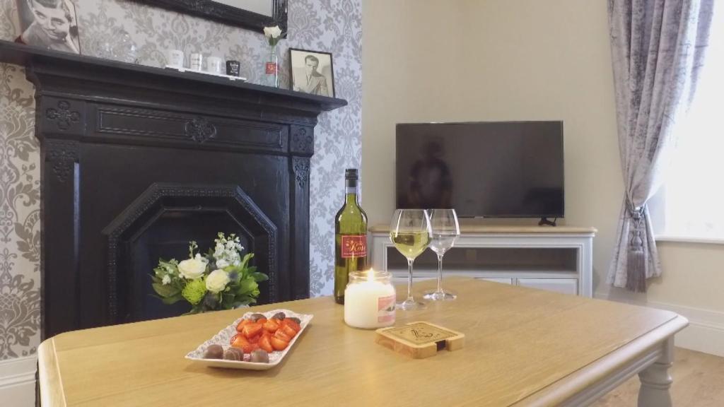 una mesa con una botella de vino y dos copas en The Rose Luxury Self Catering Accommodation, en Armagh