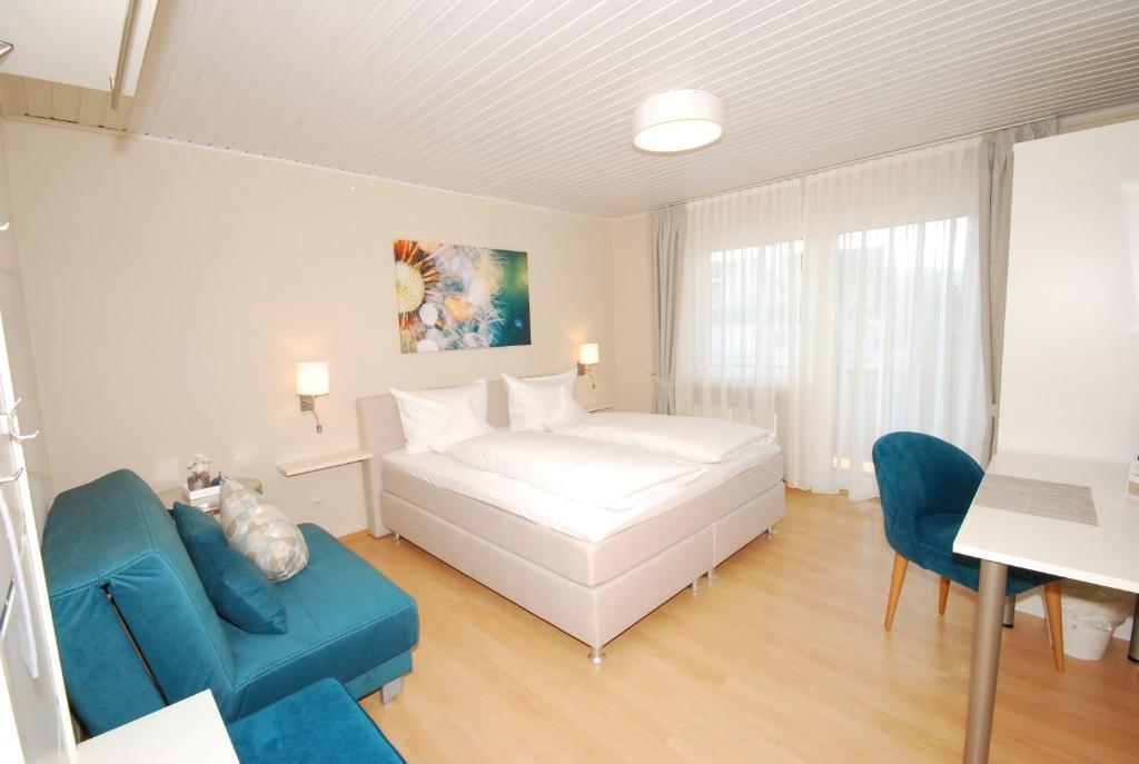 um quarto com uma cama branca e um sofá azul em Hotel Colosseum em Rheinböllen
