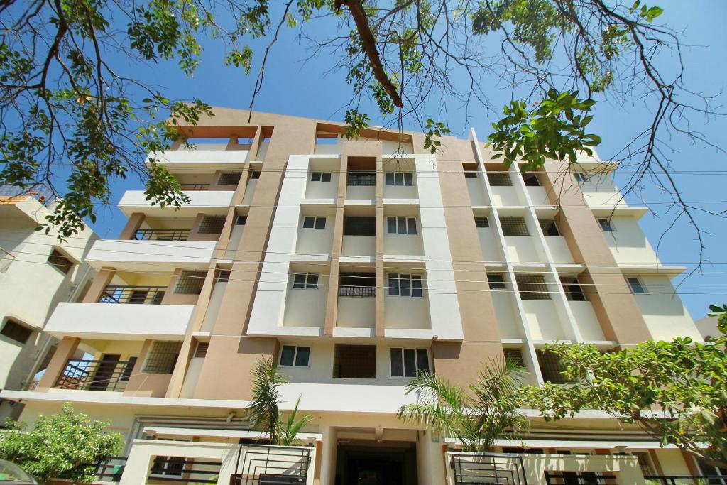 un grand bâtiment blanc avec des arbres devant lui dans l'établissement Viswa Service Apartment, à Madurai