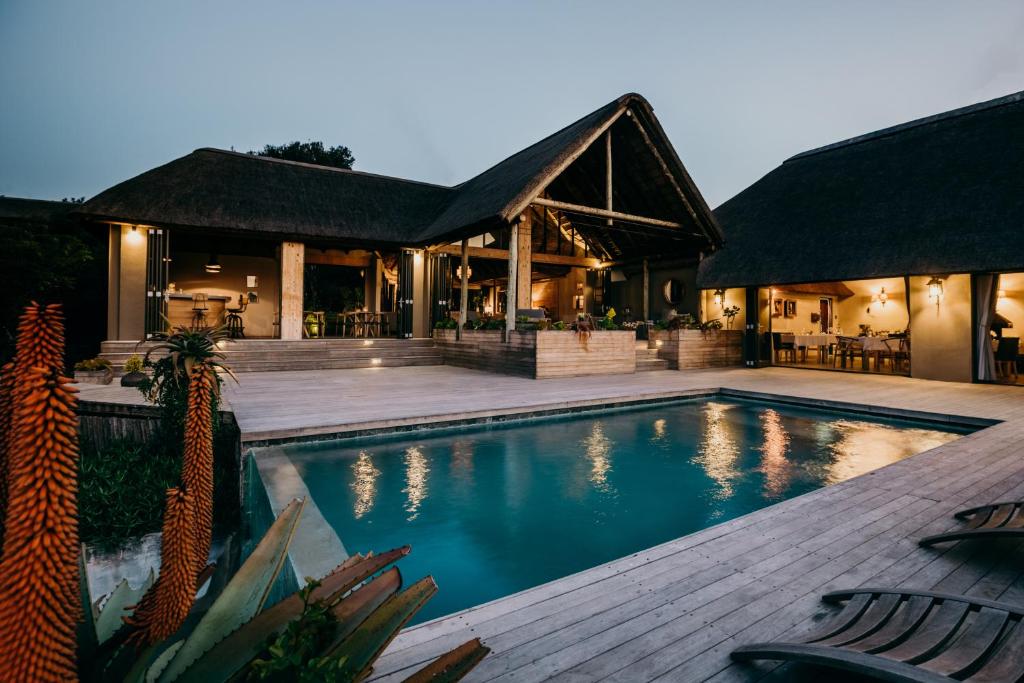 a swimming pool in front of a house at Bukela Game Lodge - Amakhala Game Reserve in Amakhala Game Reserve