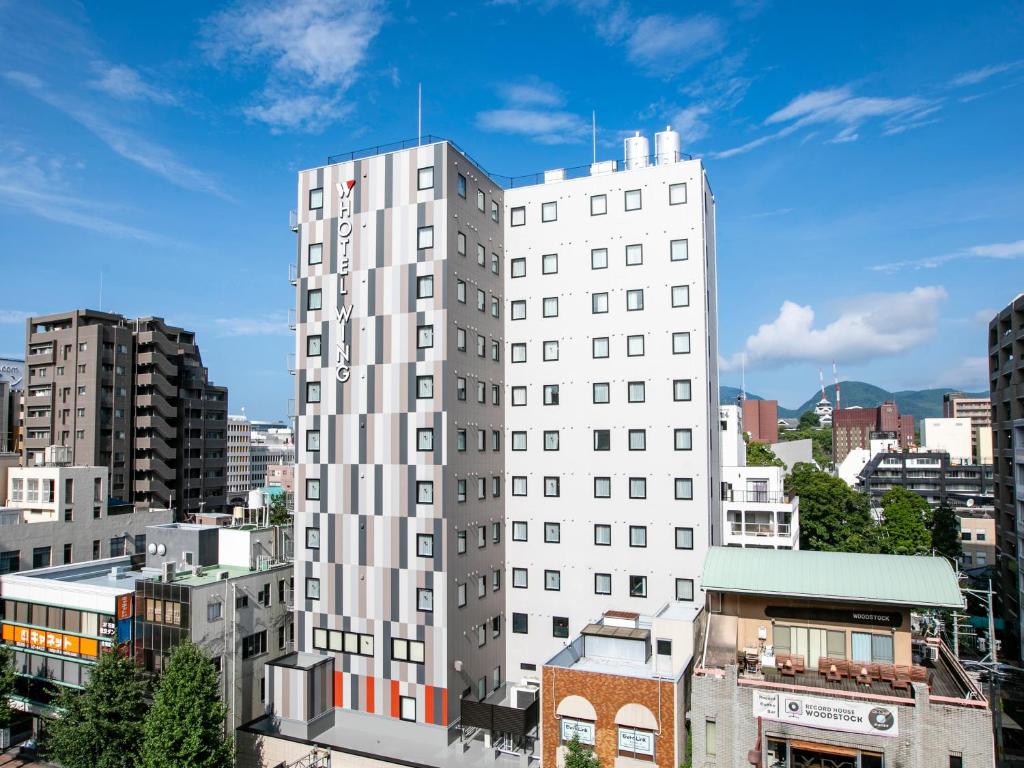 um edifício branco alto numa cidade com edifícios em Hotel Wing International Select Kumamoto em Kumamoto