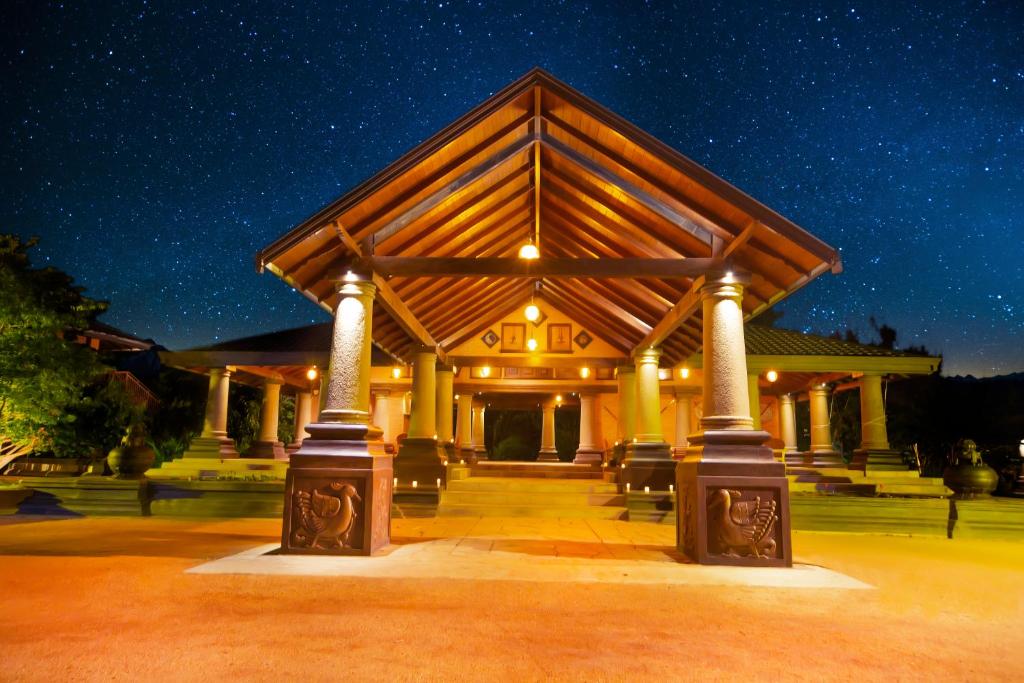a large wooden building with columns at night at Kaveri Resort Sigiriya in Sigiriya