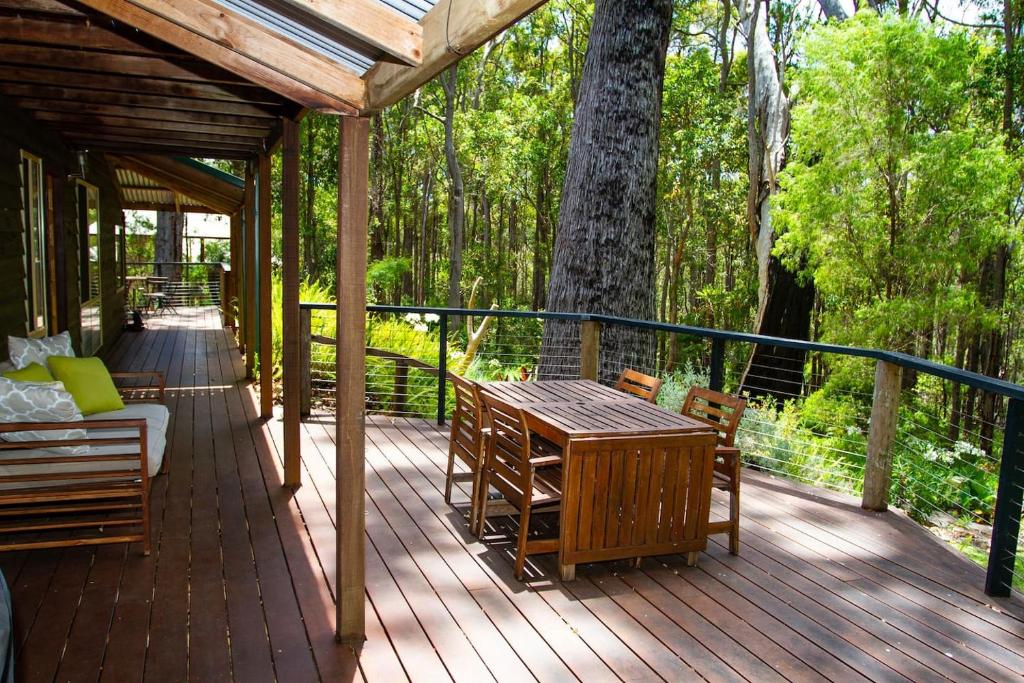 una terraza de madera con mesa y sillas. en Silvertrees en Margaret River