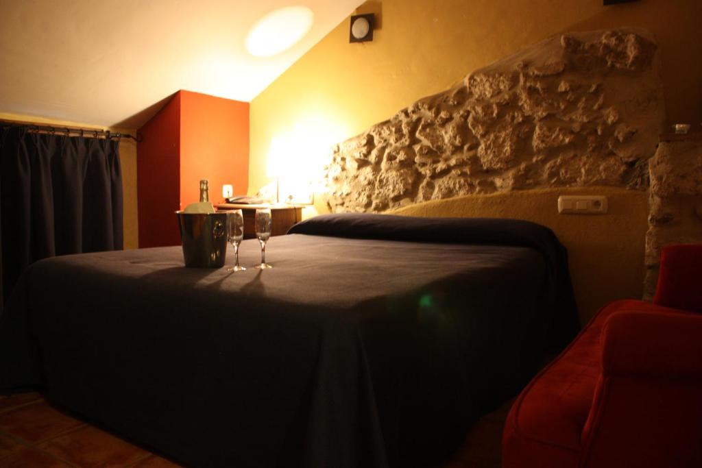 una camera da letto con un letto con due bicchieri di vino sopra di Hotel Don Pero ad Alora