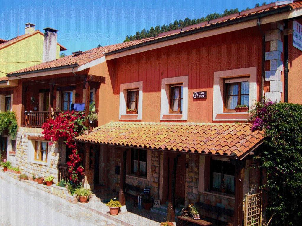 a large red building with flowers in front of it at Casa Rural Casa Pipo in Colunga